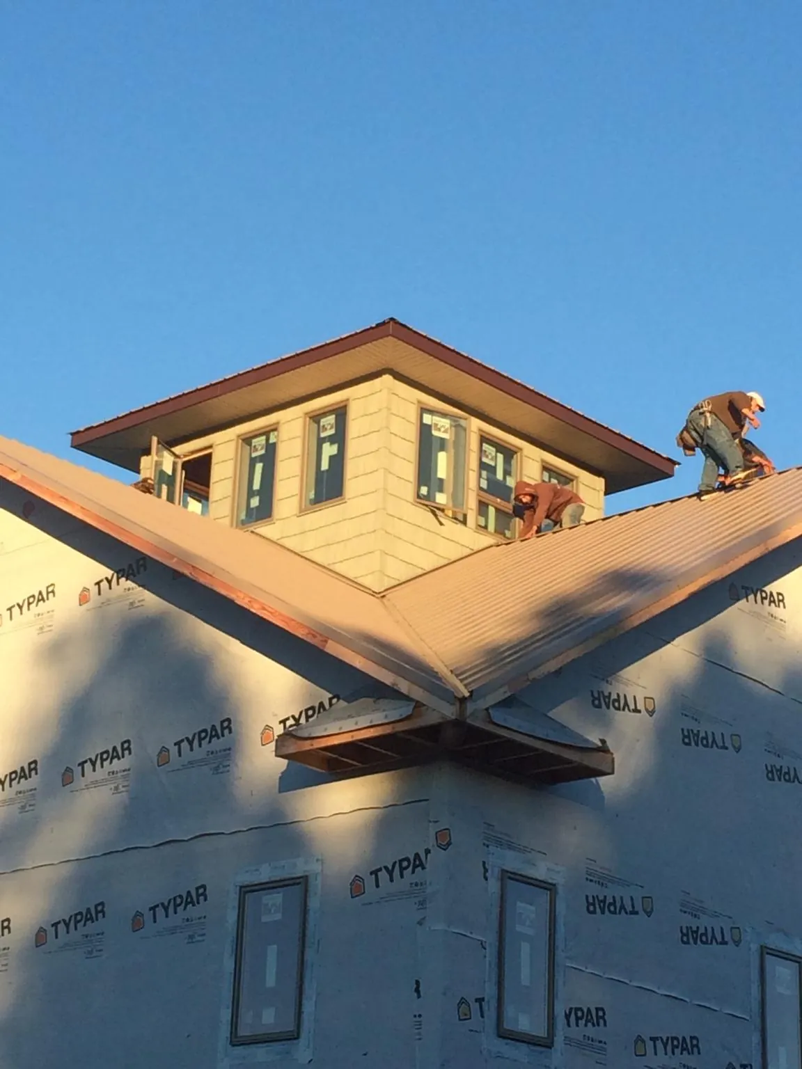 Roofers working around a rooftop cupola on a new metal roof at sunset — Roof Waterproofing in Ashville by Roofing Brothers
